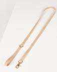 Beige dog lead with a gold clasp on a light gray background
