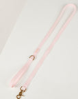 Pink dog lead with a gold clasp on a light gray background
