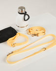 Black pouch, white water bottle with black handle, and yellow dog leashes on a light gray background
