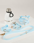 Light blue dog collar, leash, and harness set with a white water bottle on a light gray background