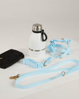 White thermos with black handle, black pouch, and light blue dog leashes on a white background