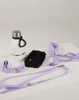 Lavender dog collar, leash, and harness on a white surface with a white water bottle.