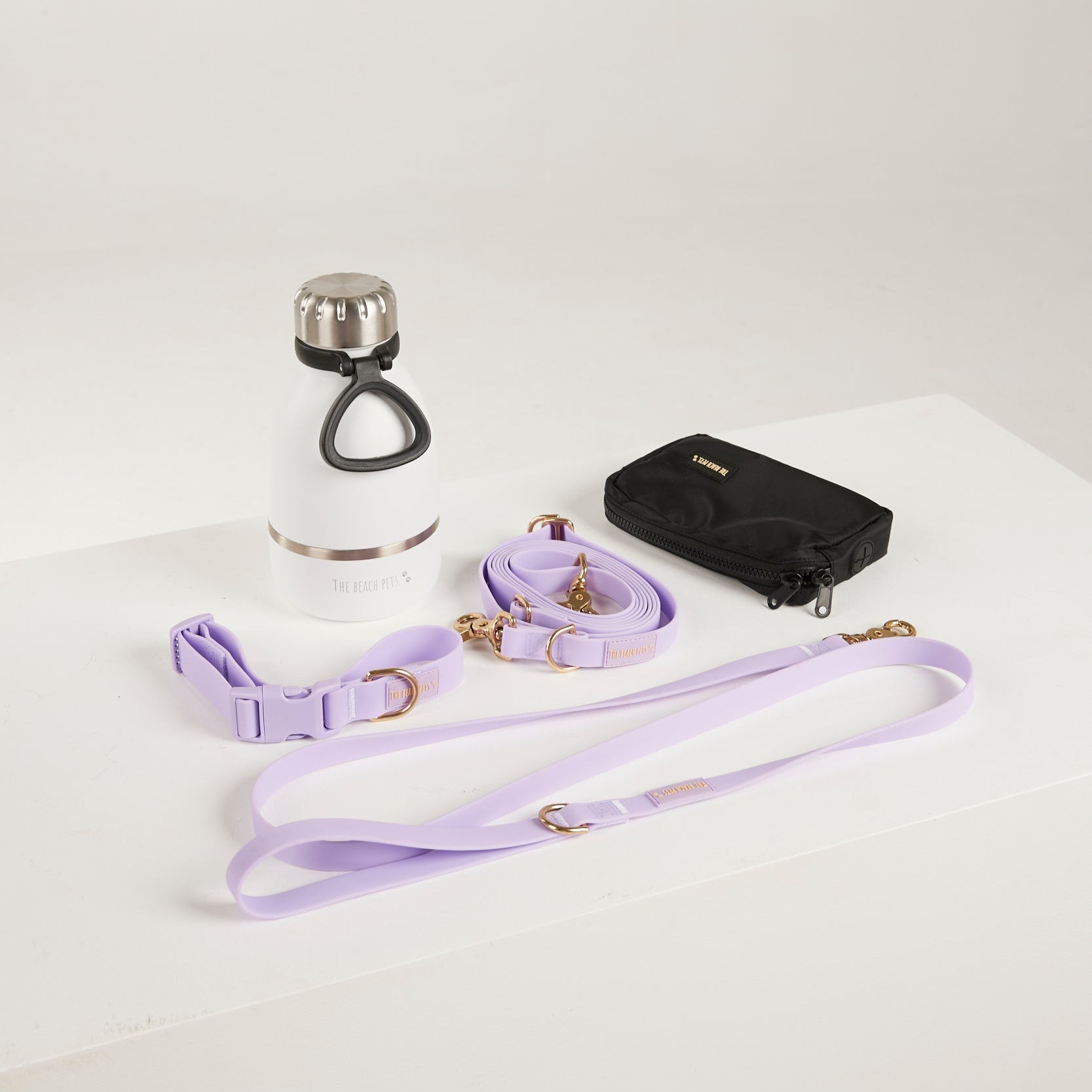 Dog collar, leash, and water bottle on a white surface
