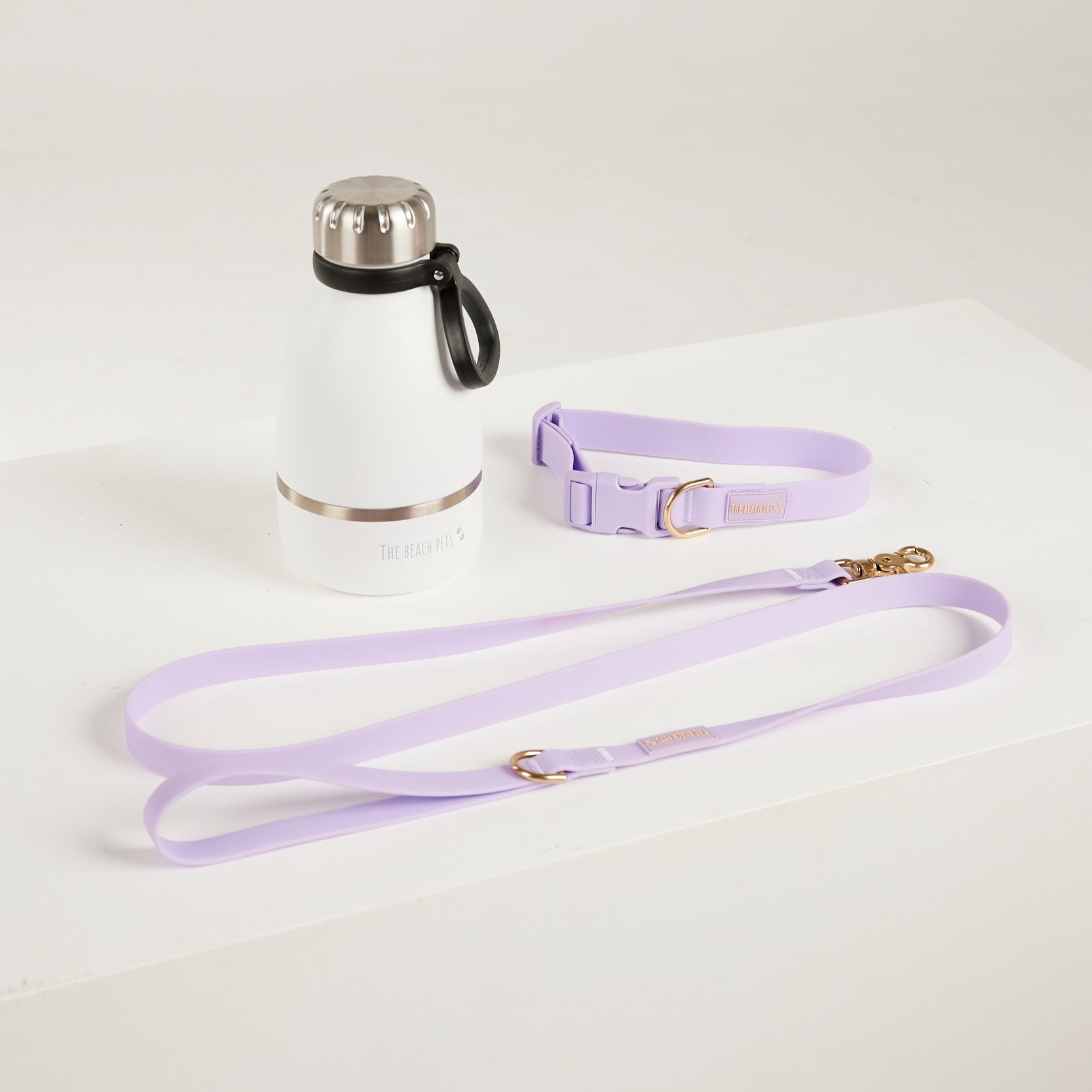 Lavender dog leash and collar with a water bottle on a light gray background