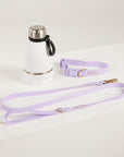 Lavender dog leash and collar with a water bottle on a light gray background