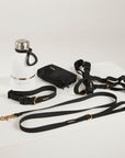 Collection of dog accessories including a water bottle, leash, and collar on a light gray background.