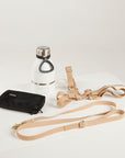 Black pouch, white water bottle with silver cap, and beige dog leashes on a light gray background