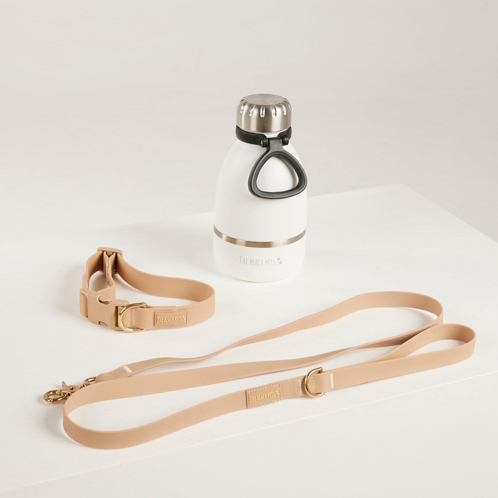 White water bottle with black cap and beige leash on a white background
