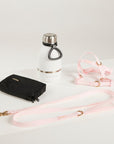 White water bottle with black cap, black wallet, and pink leash on a light gray background