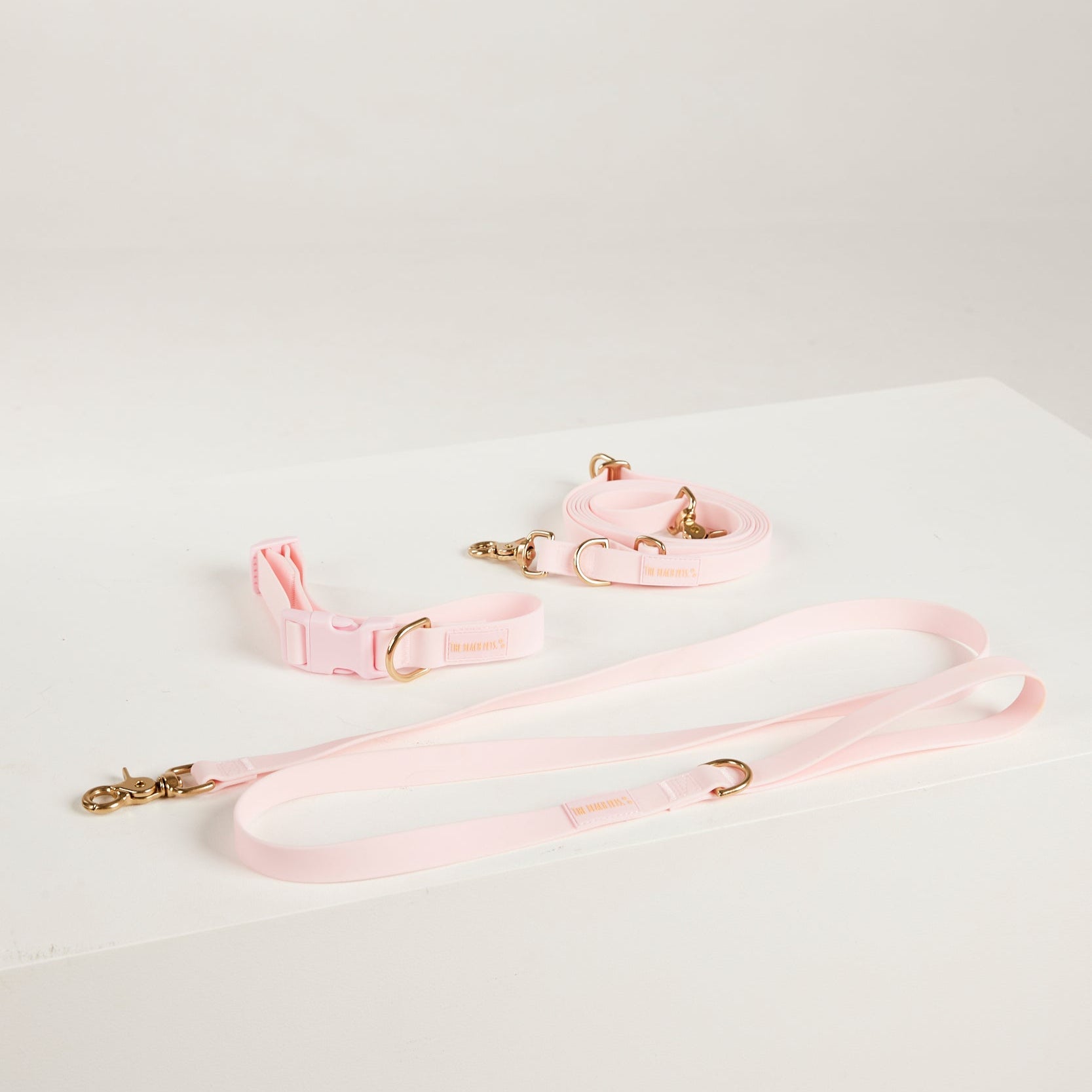 Pink dog collar and leash set on a light gray background