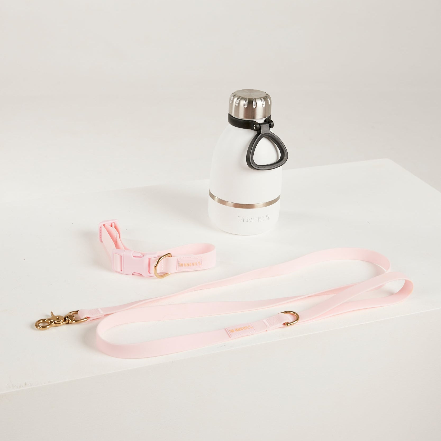 White water bottle with black cap and pink leash on a white background