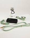 Set of green dog leash, black wallet, and white water bottle with silver cap on a light gray background