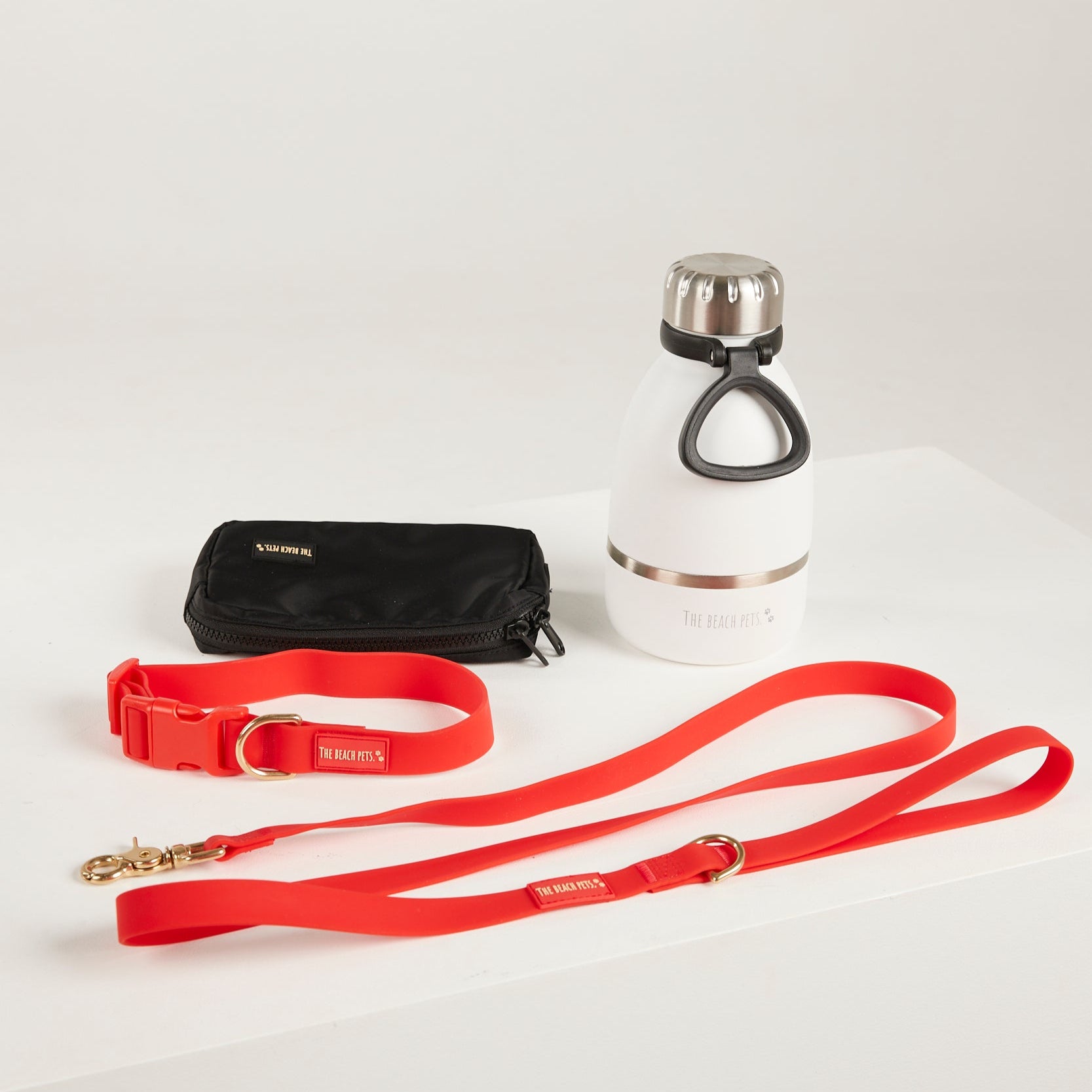 red dog lead, dog collar, bottle and poop bag