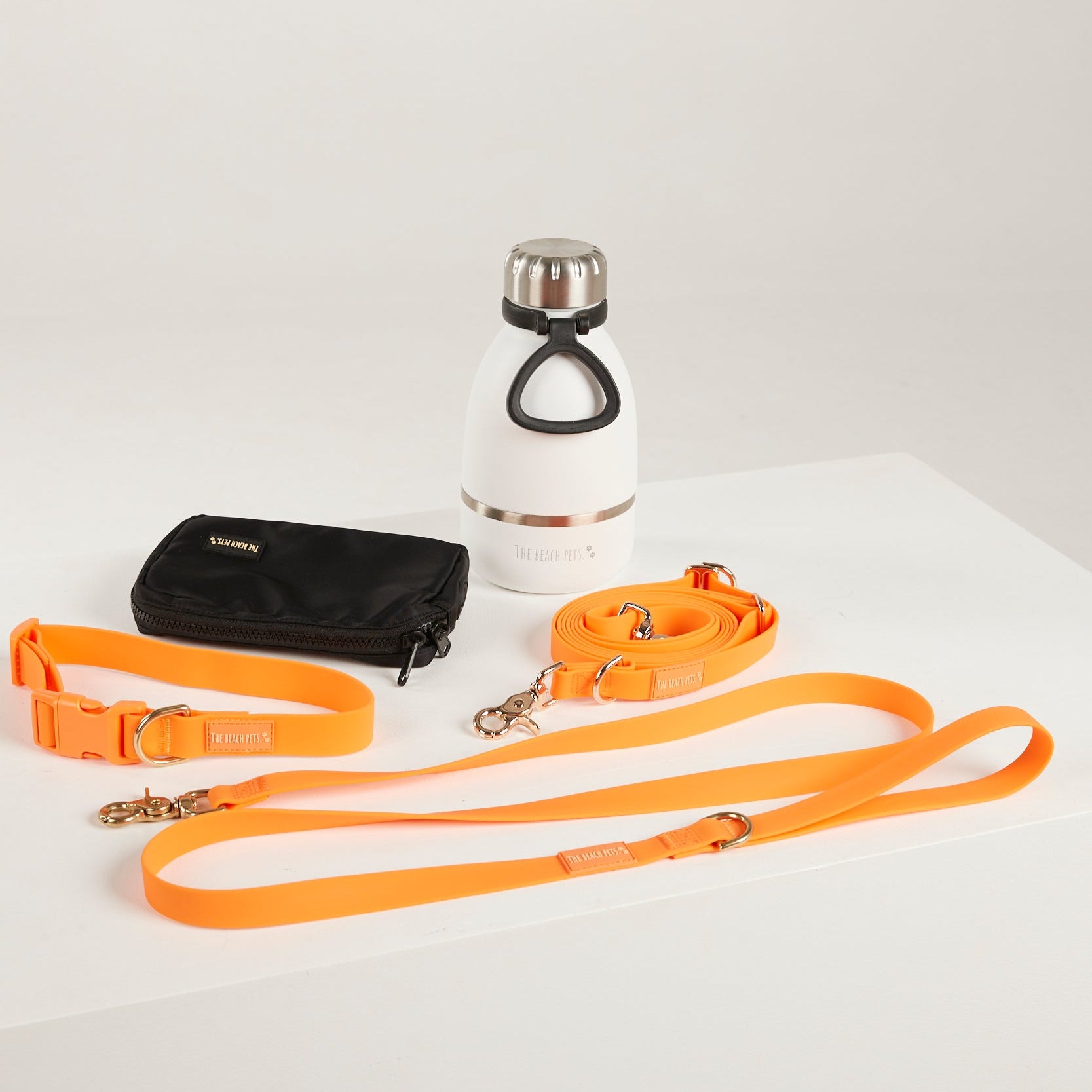 Dog leash, water bottle, and pouch on a white surface