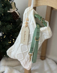 Green dog harness on a knitted christmas stocking with a Christmas tree in the background