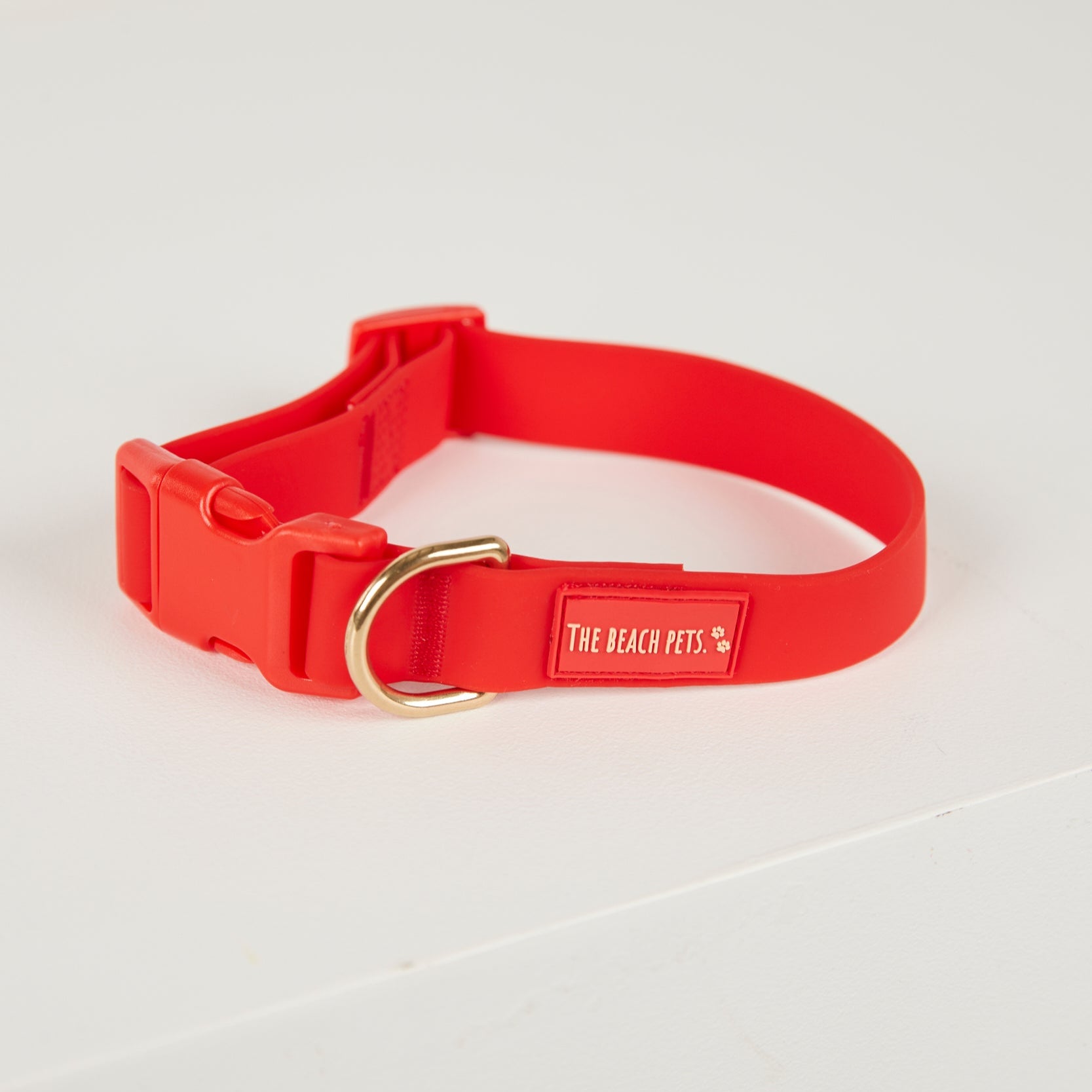 Red dog collar with a gold buckle on a white background