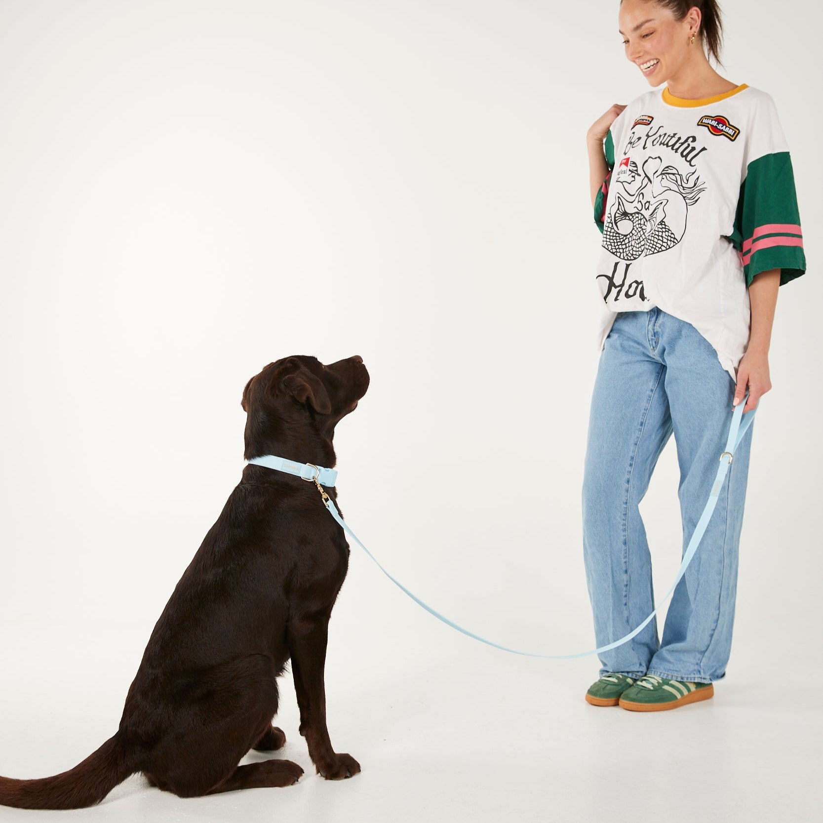 Woman standing next to a black dog on a white background