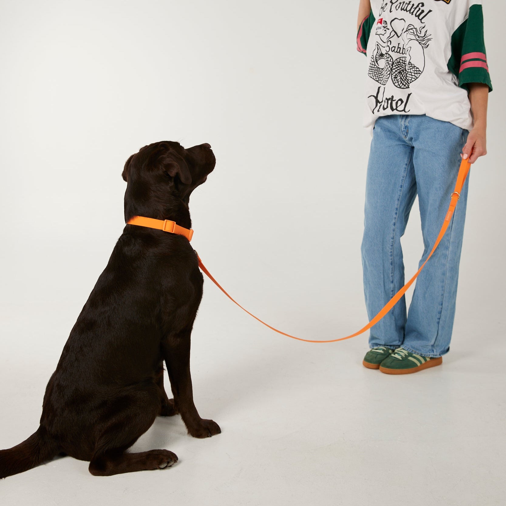 Woman standing next to a black dog on a white background