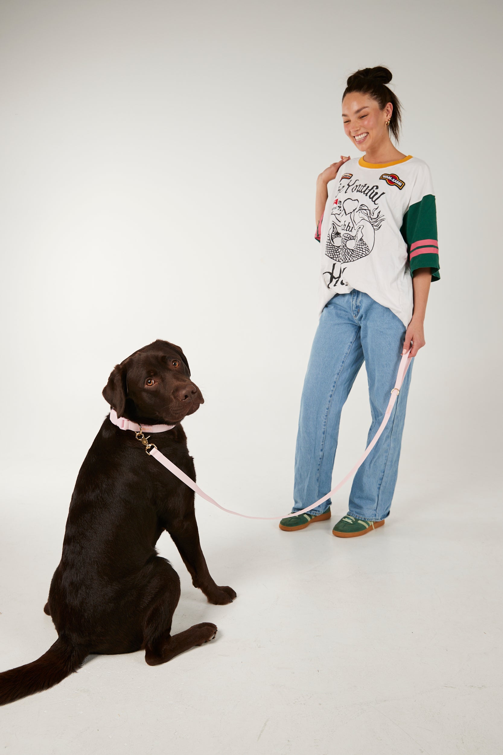 Woman standing next to a black dog on a white background