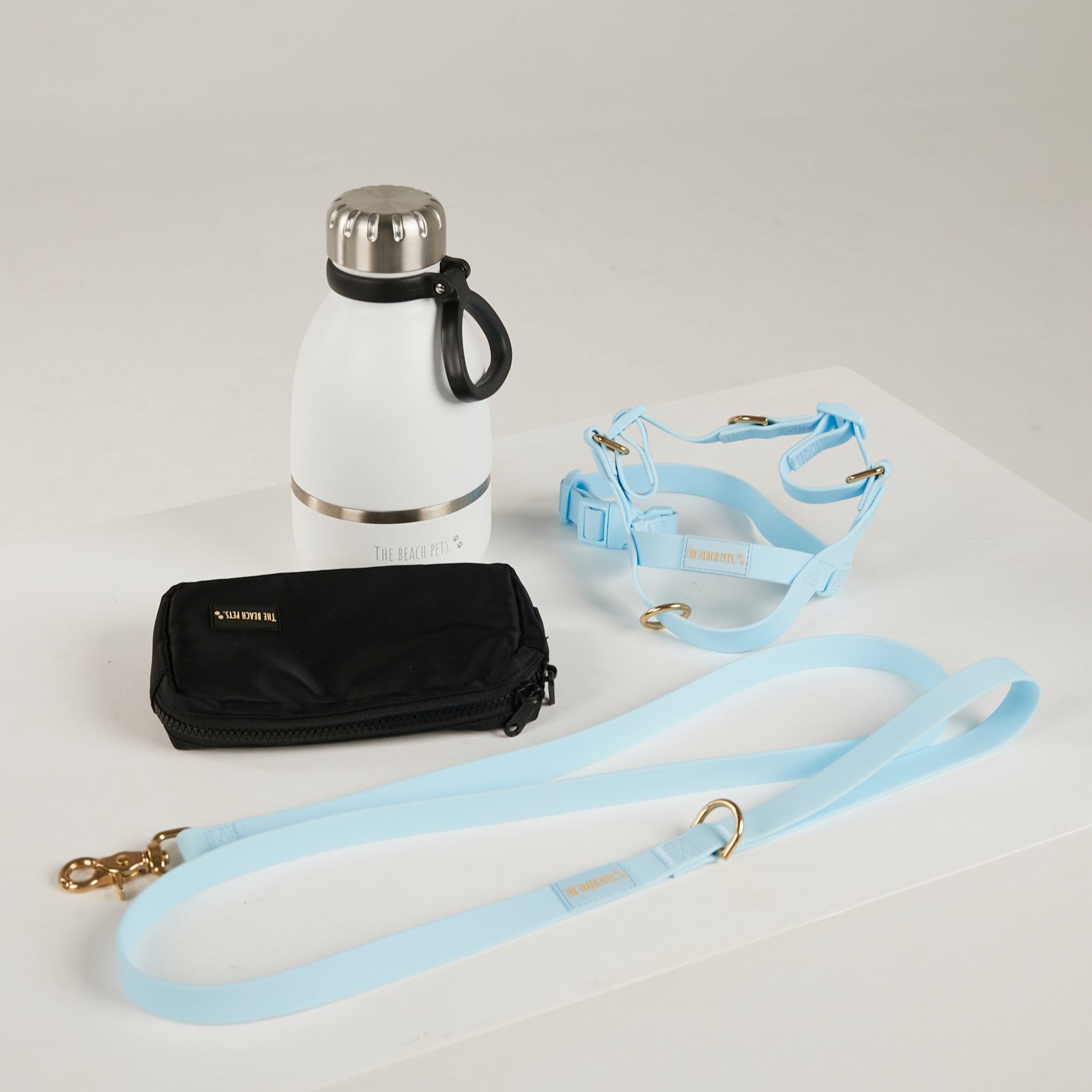 White thermos, black wallet, and light blue strap on a white background