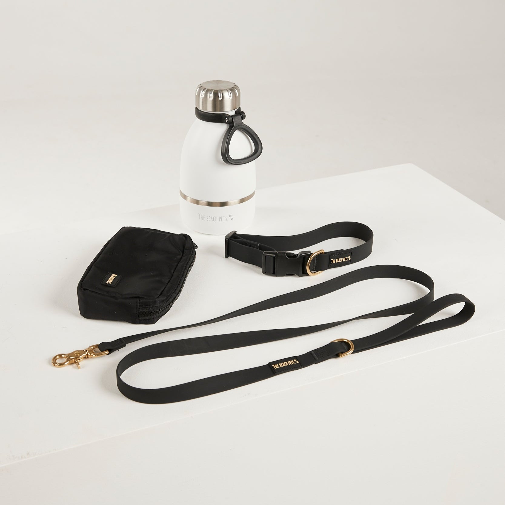 black dog lead, dog collar, bottle and poop bag 