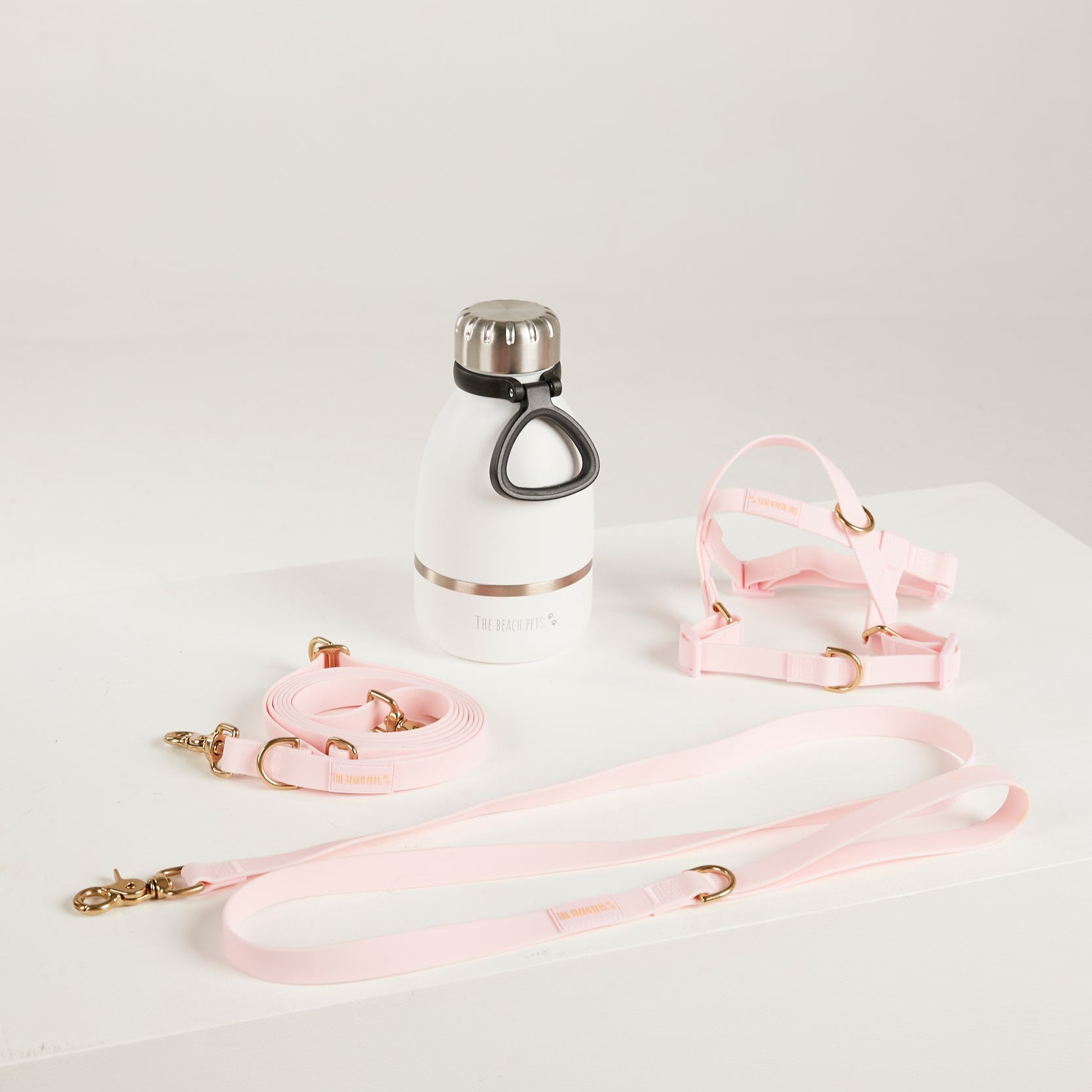 pink  dog lead, harness, and botte 