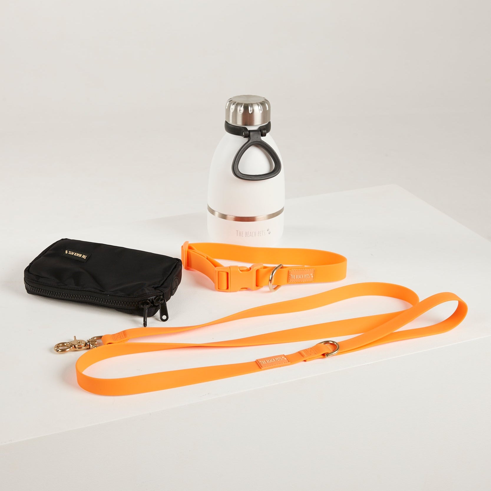 orange dog lead, dog collar, bottle and poop bag  