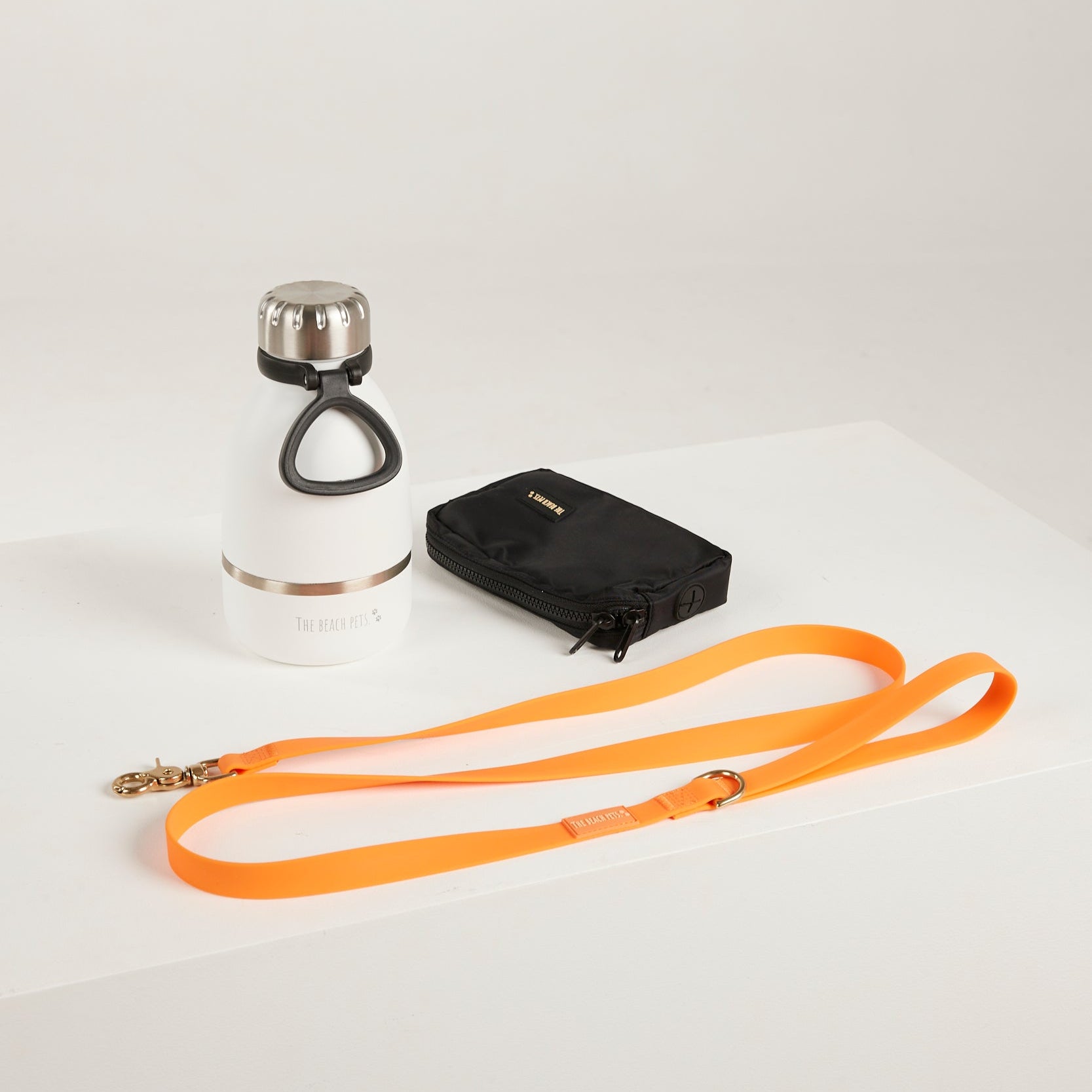 orange  dog leash, dog poop bag and dog waterbottle